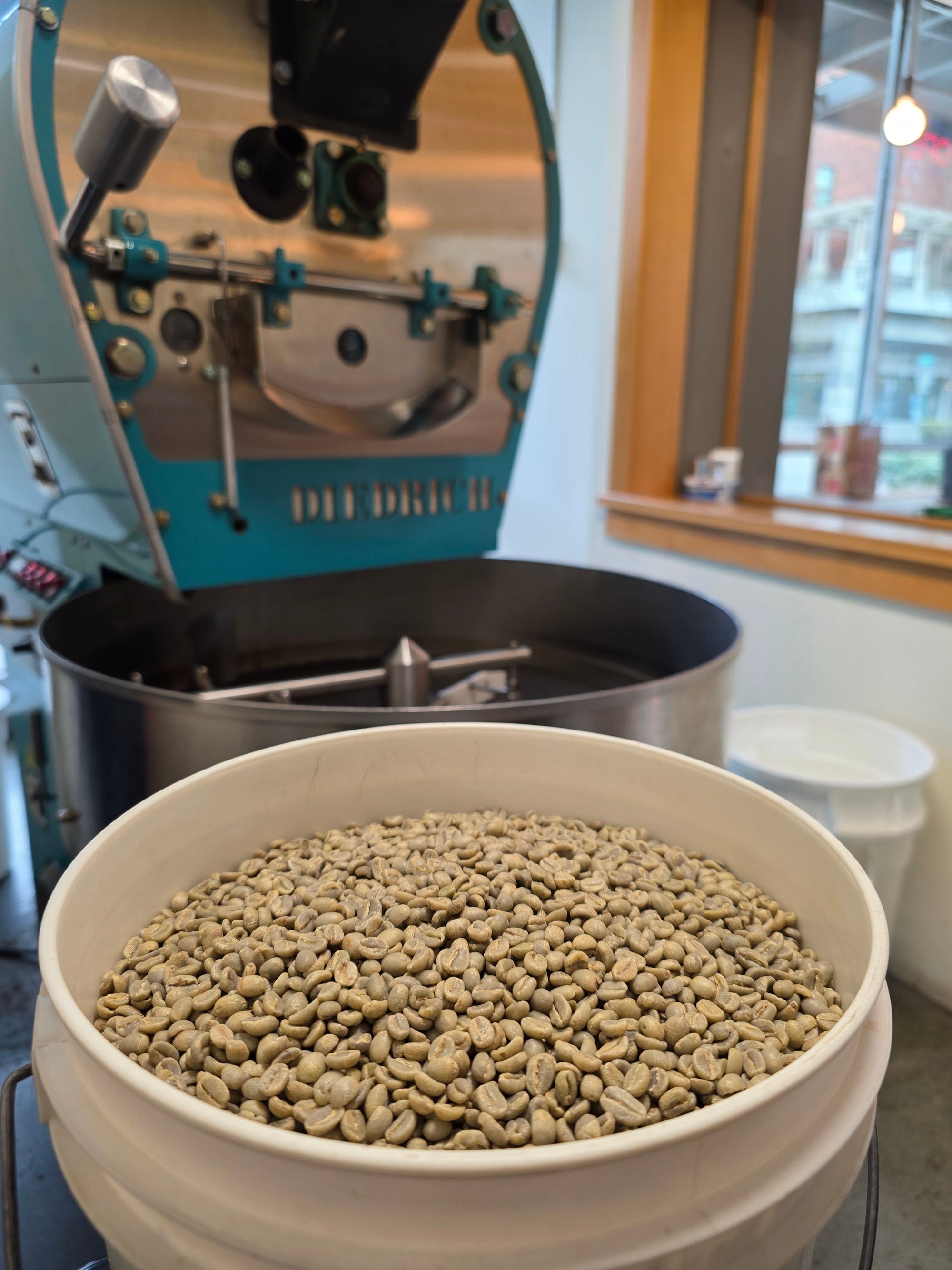 bucket of green coffee beans waiting to go into coffee roasting machine