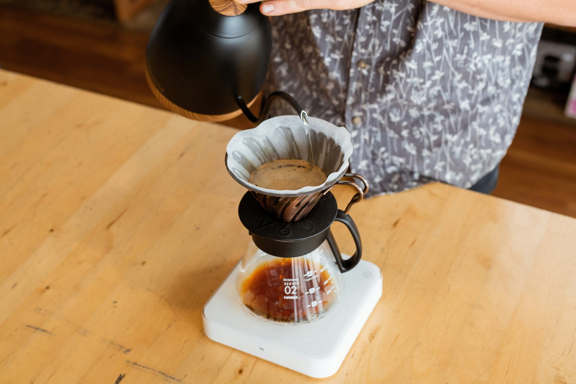 gooseneck kettle pouring water into pourover coffee brewer on digital scale