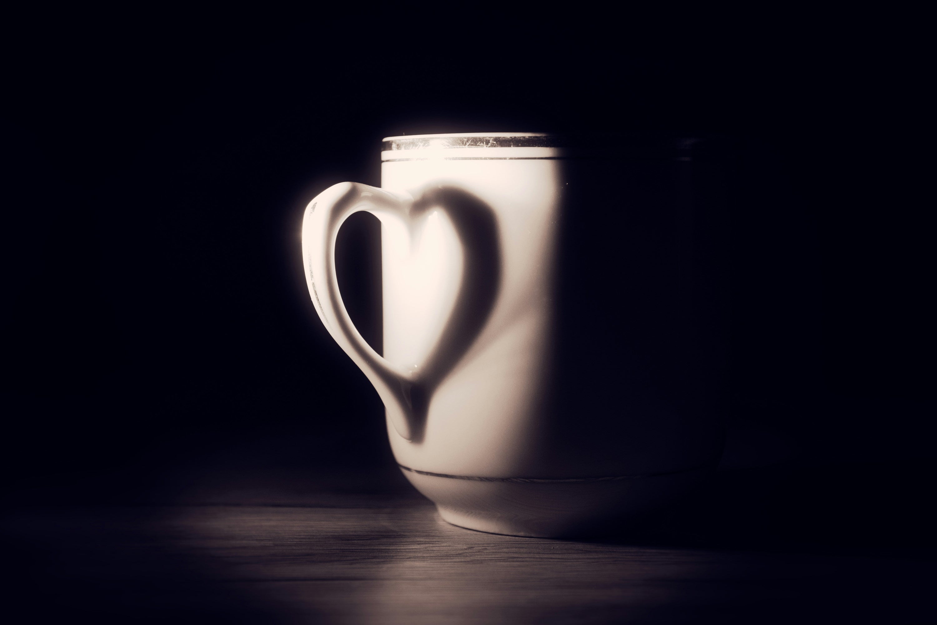 COFFEE CUP WITH CUP HANDLE AND SHADOW FORMING A HEART SHAPE