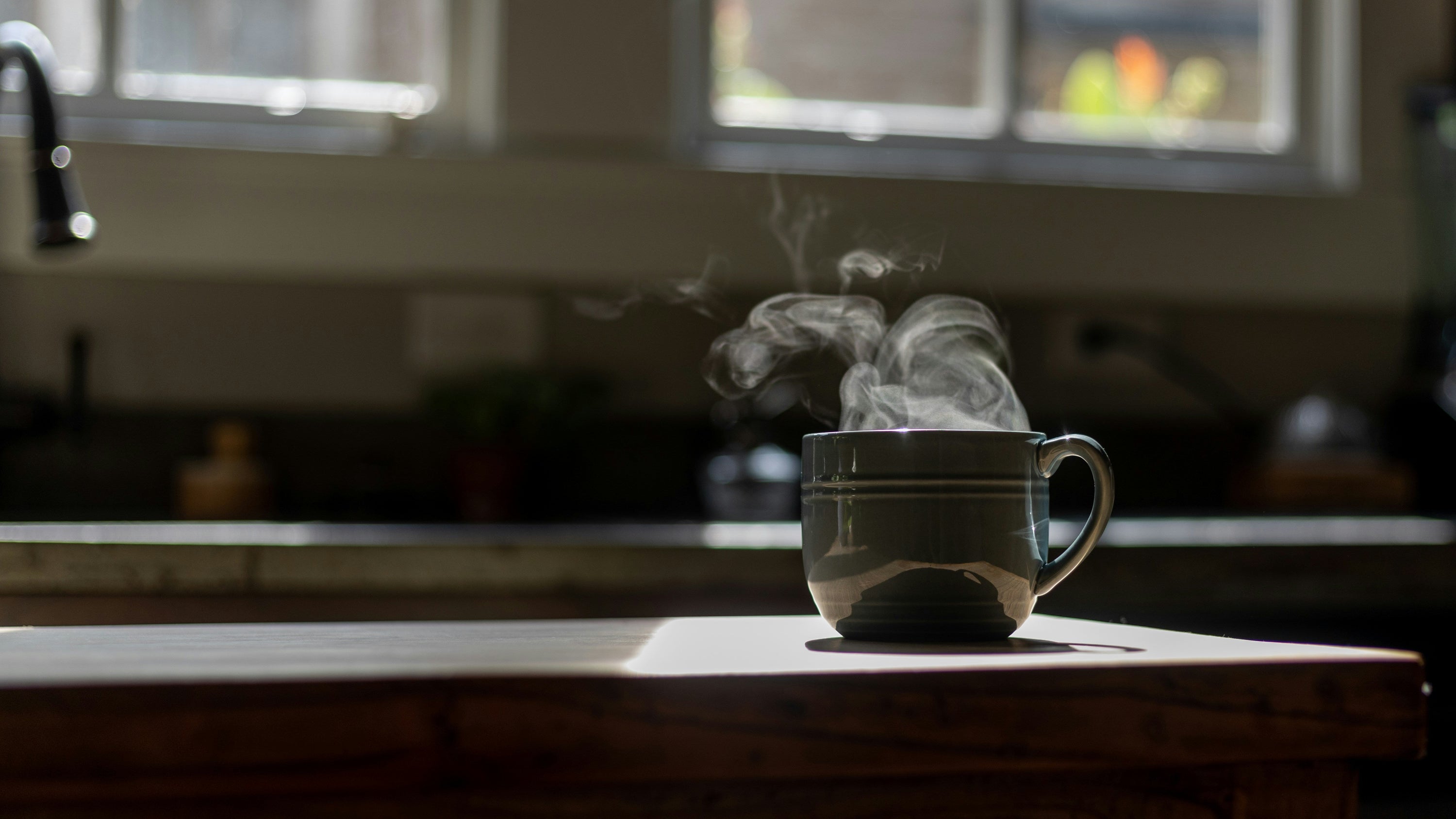 steaming cup of coffee in sunlight