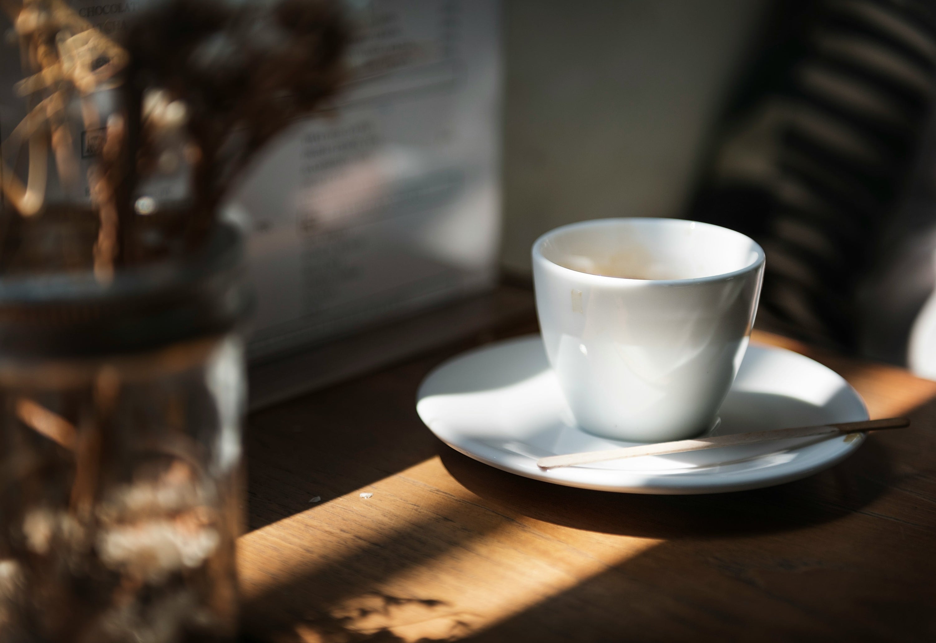 white espresso cup sitting on white saucer on wooden countertop
