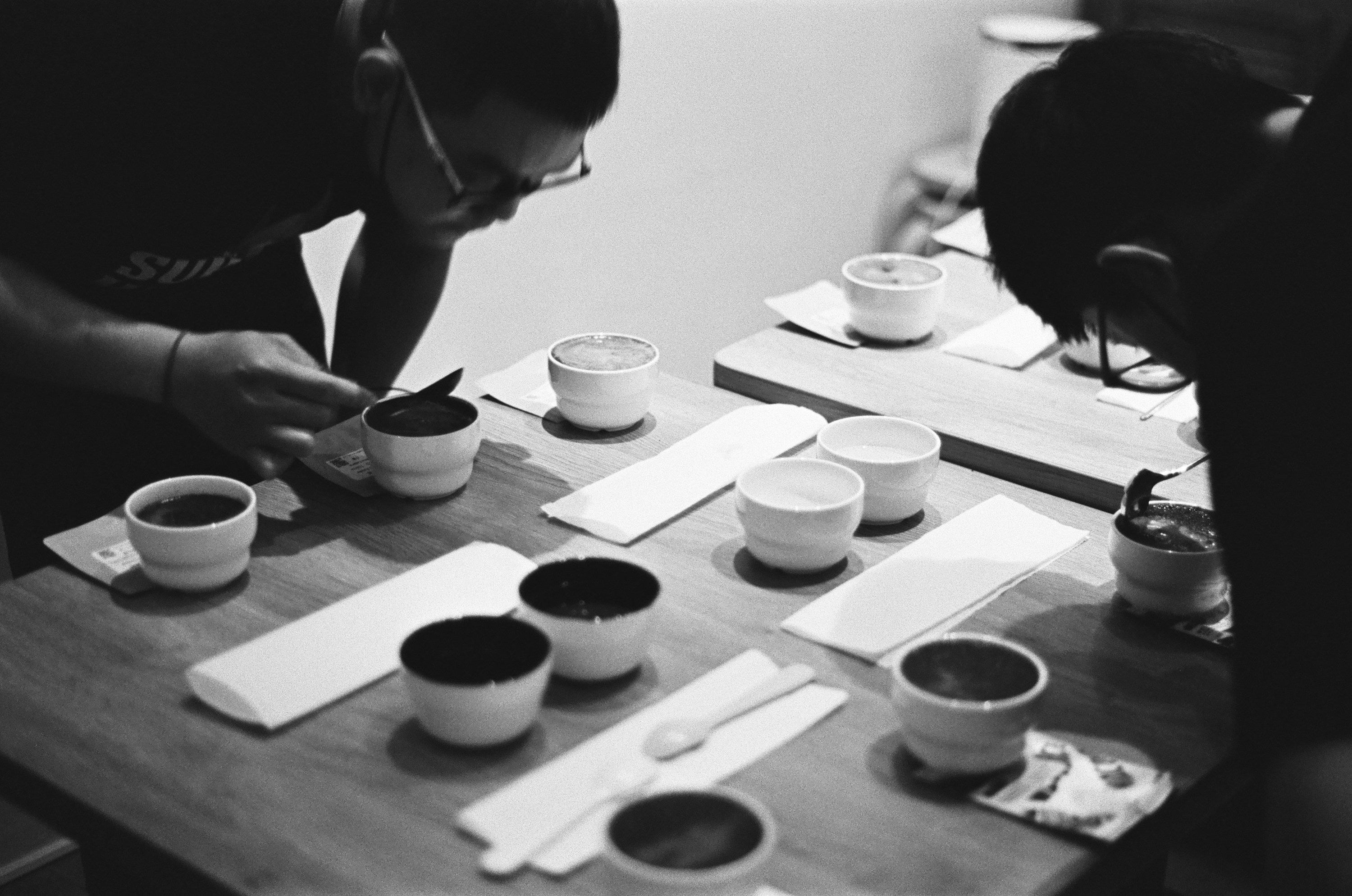 black and white photo of 2 people tasting coffee