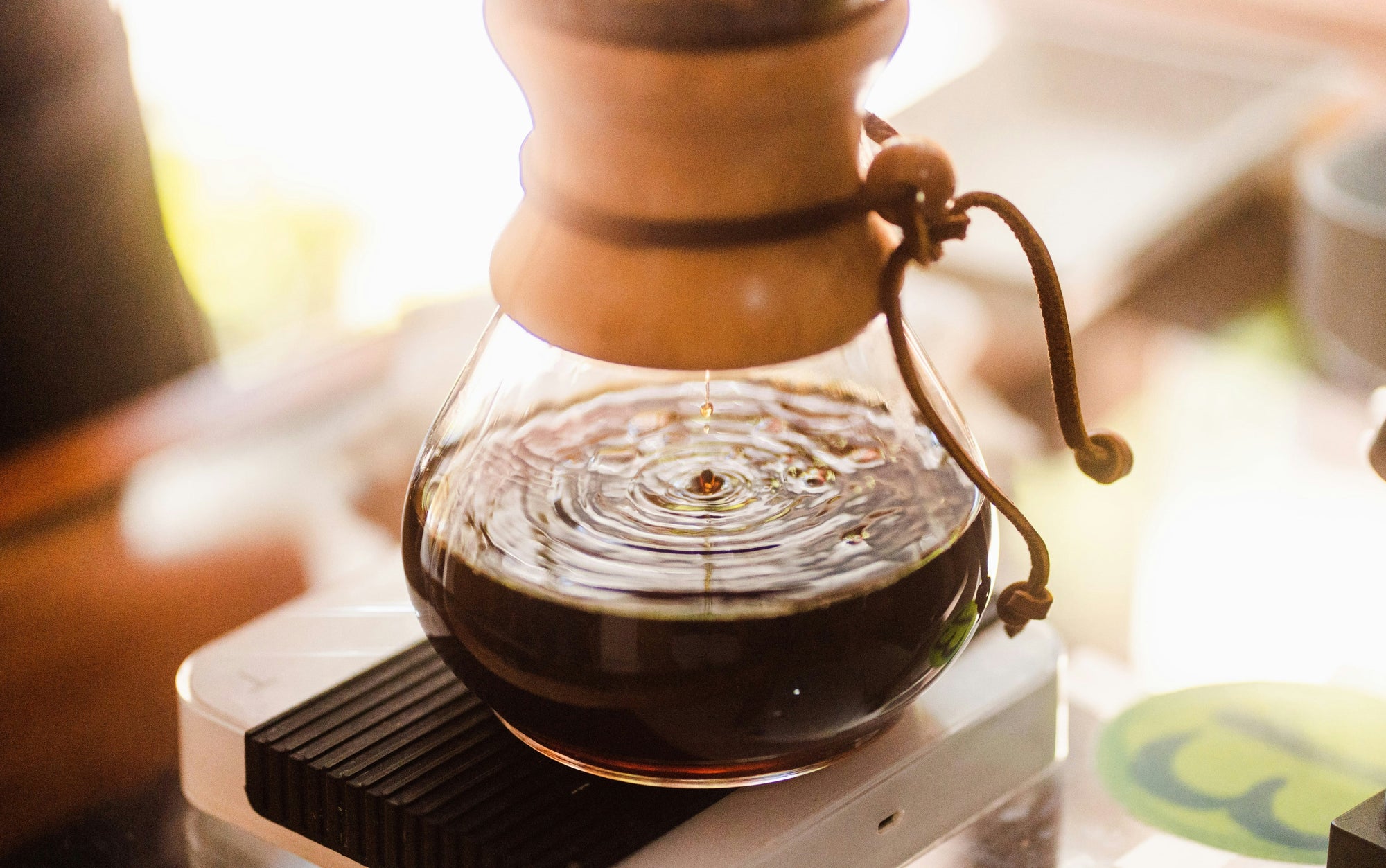 chemex coffee maker in sunlight with coffee dripping brewing through it