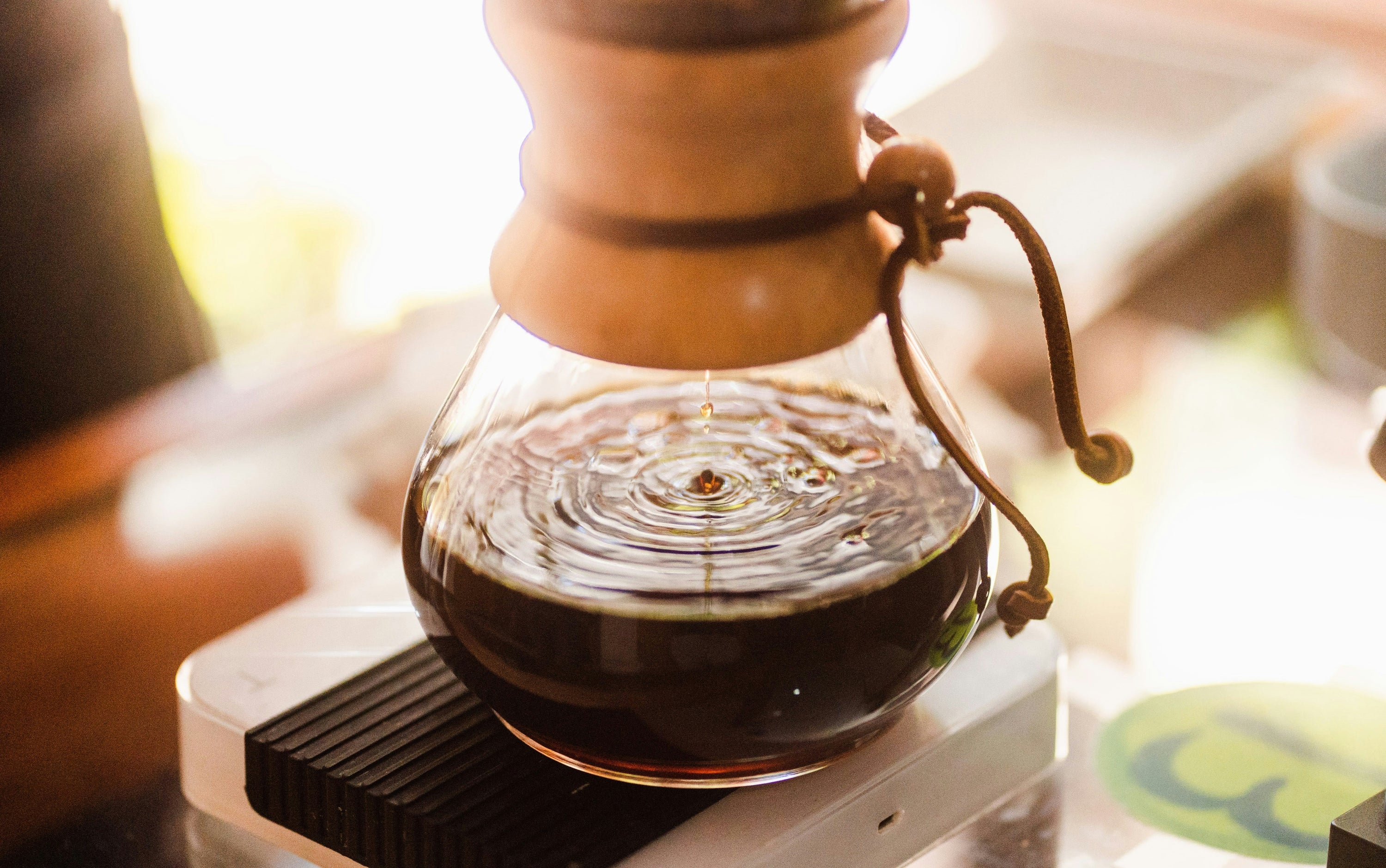 chemex coffee maker in sunlight with coffee dripping brewing through it