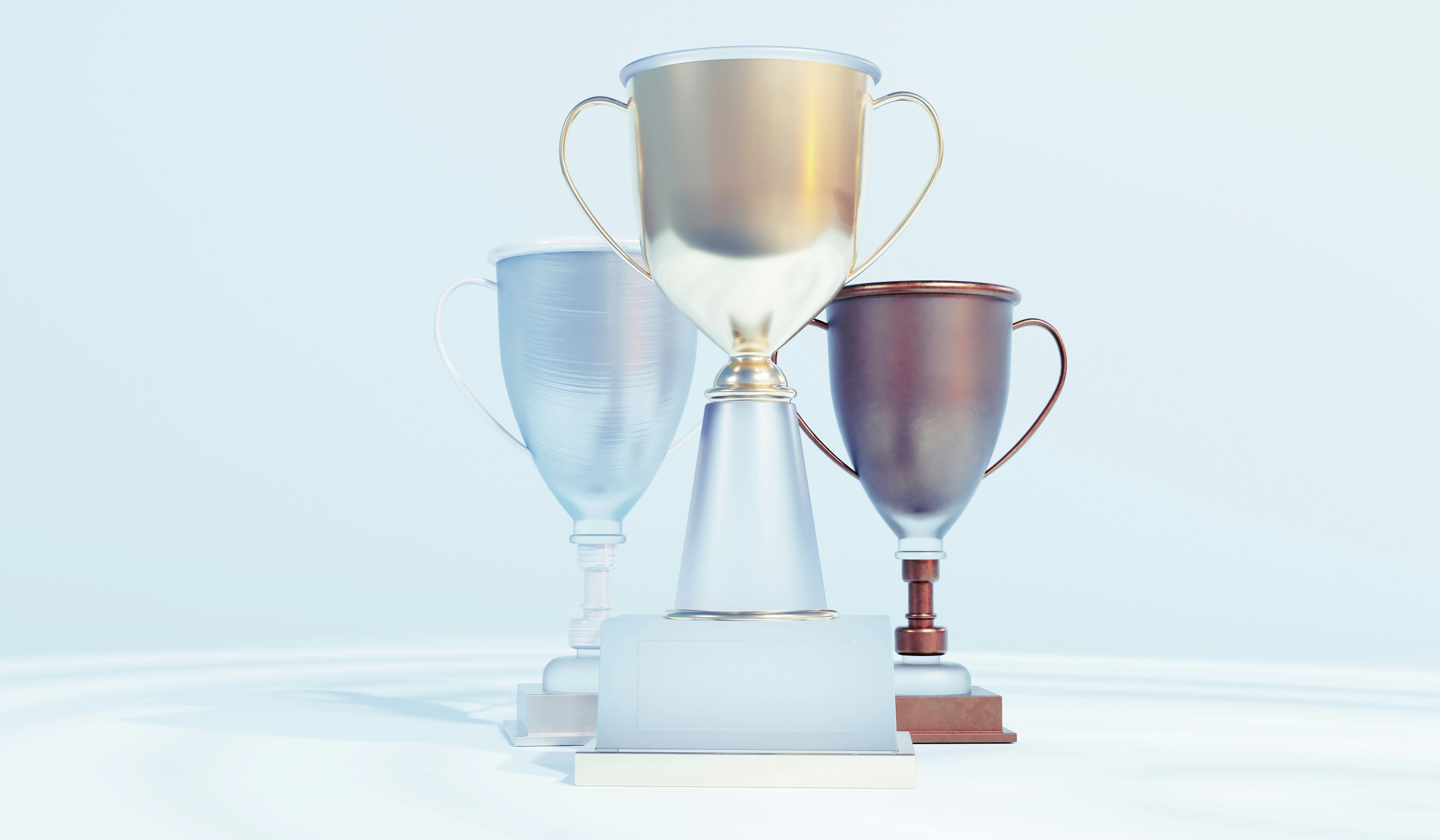 three trophies sitting against pale background
