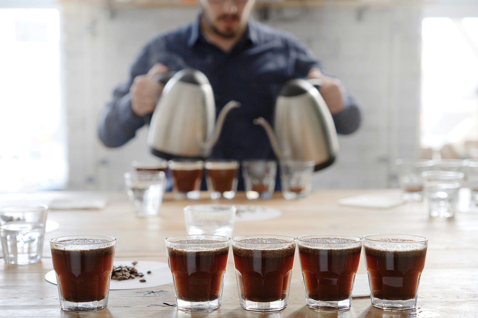 person coffee cupping with multiple cups of coffee waiting for tasting