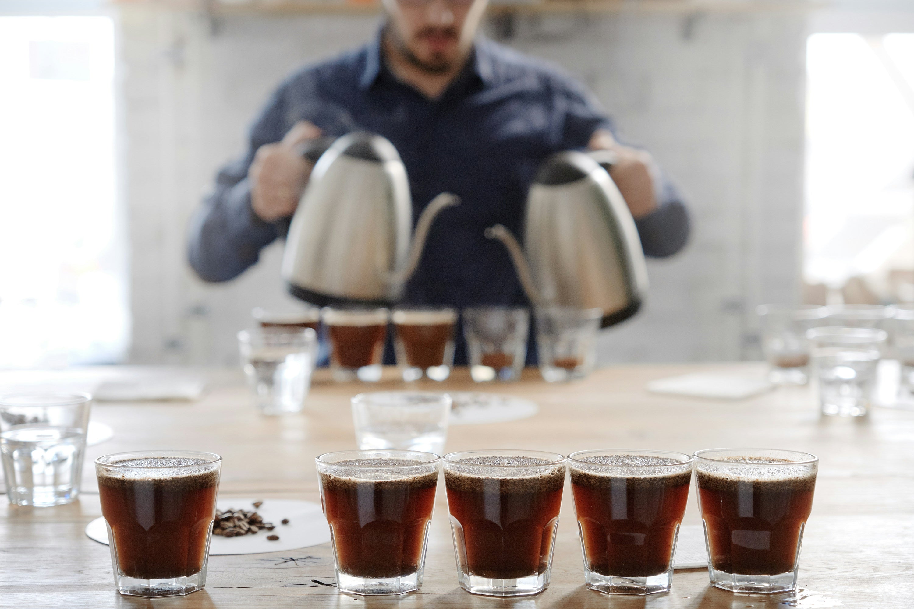 person coffee cupping with multiple cups of coffee waiting for tasting