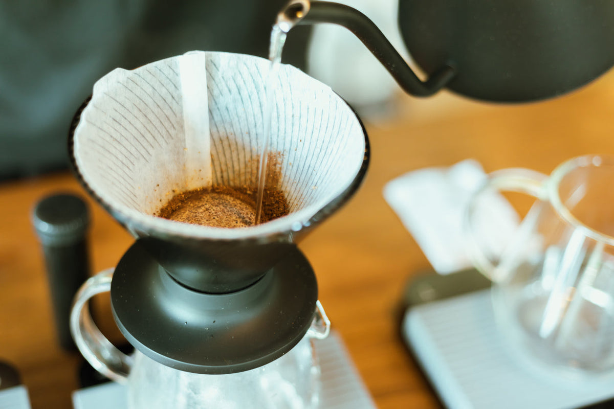 Hot water being poured from kettle into pour over coffee maker