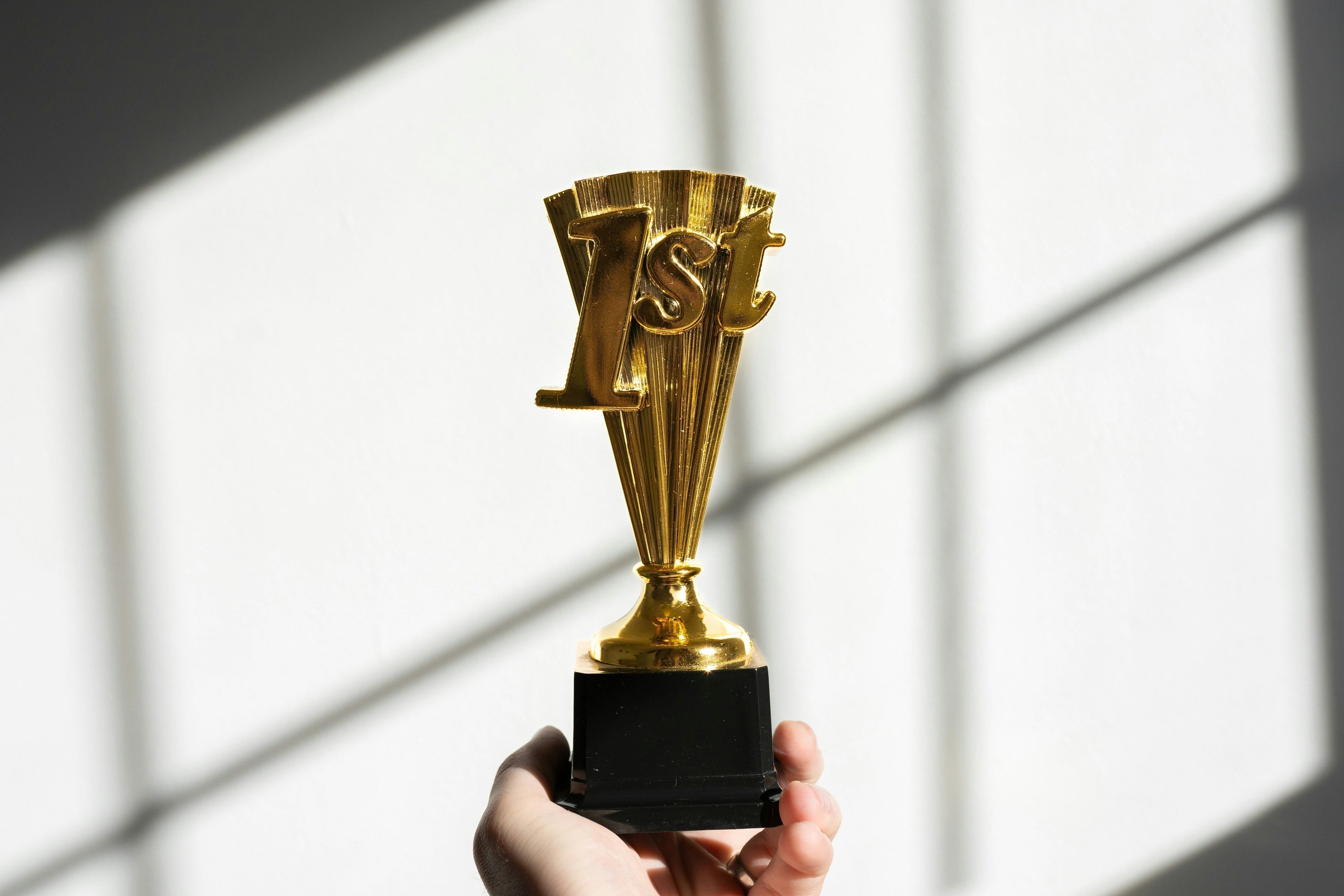 hand holding gold trophy with 1st written on it