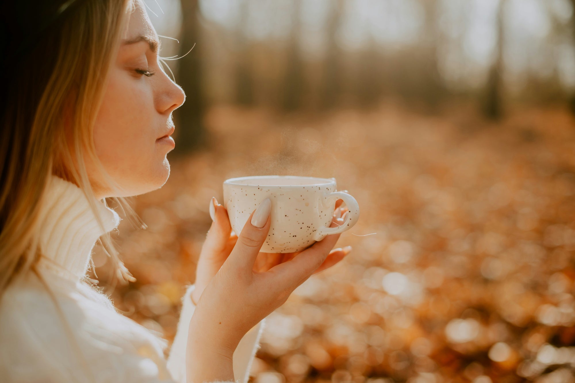 lady smelling aroma of coffee in an autumnal wood