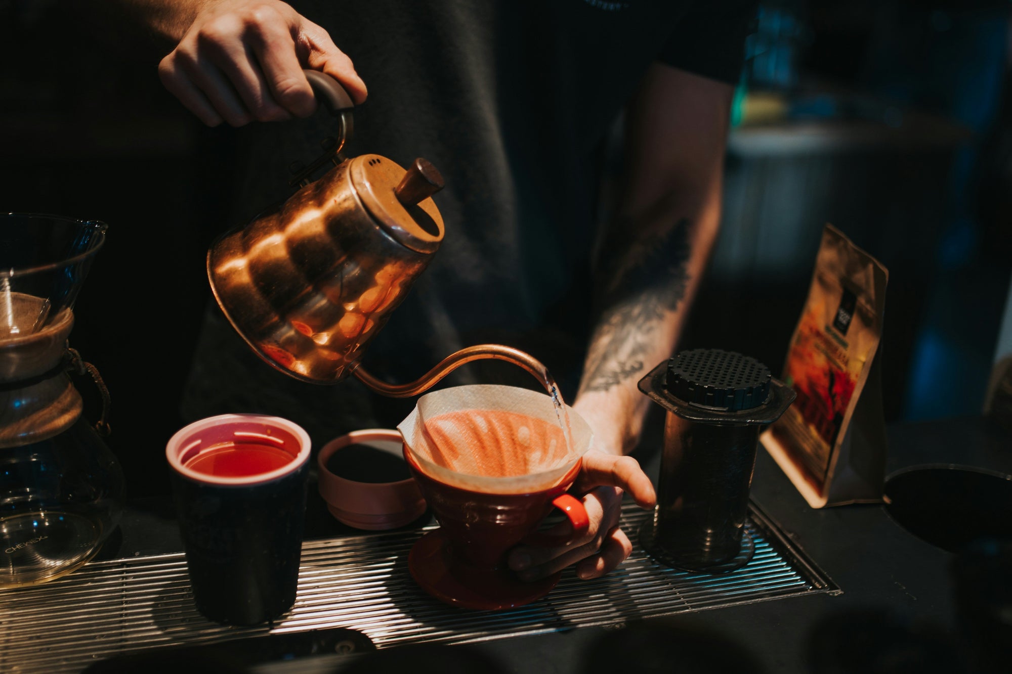 water being poured from kettle over pour over red coffee dripper