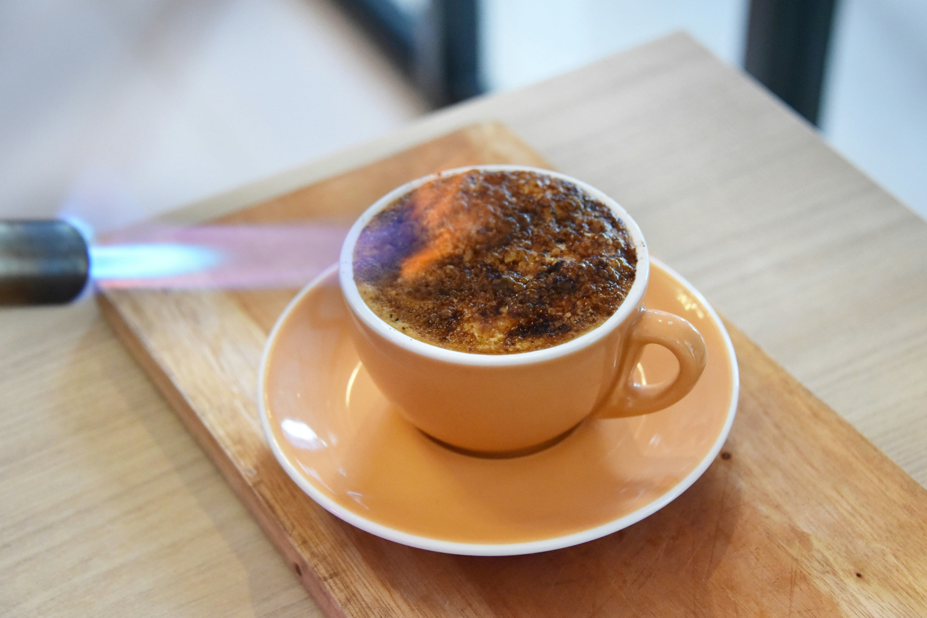 a blowtorch burning the top of a latte coffee