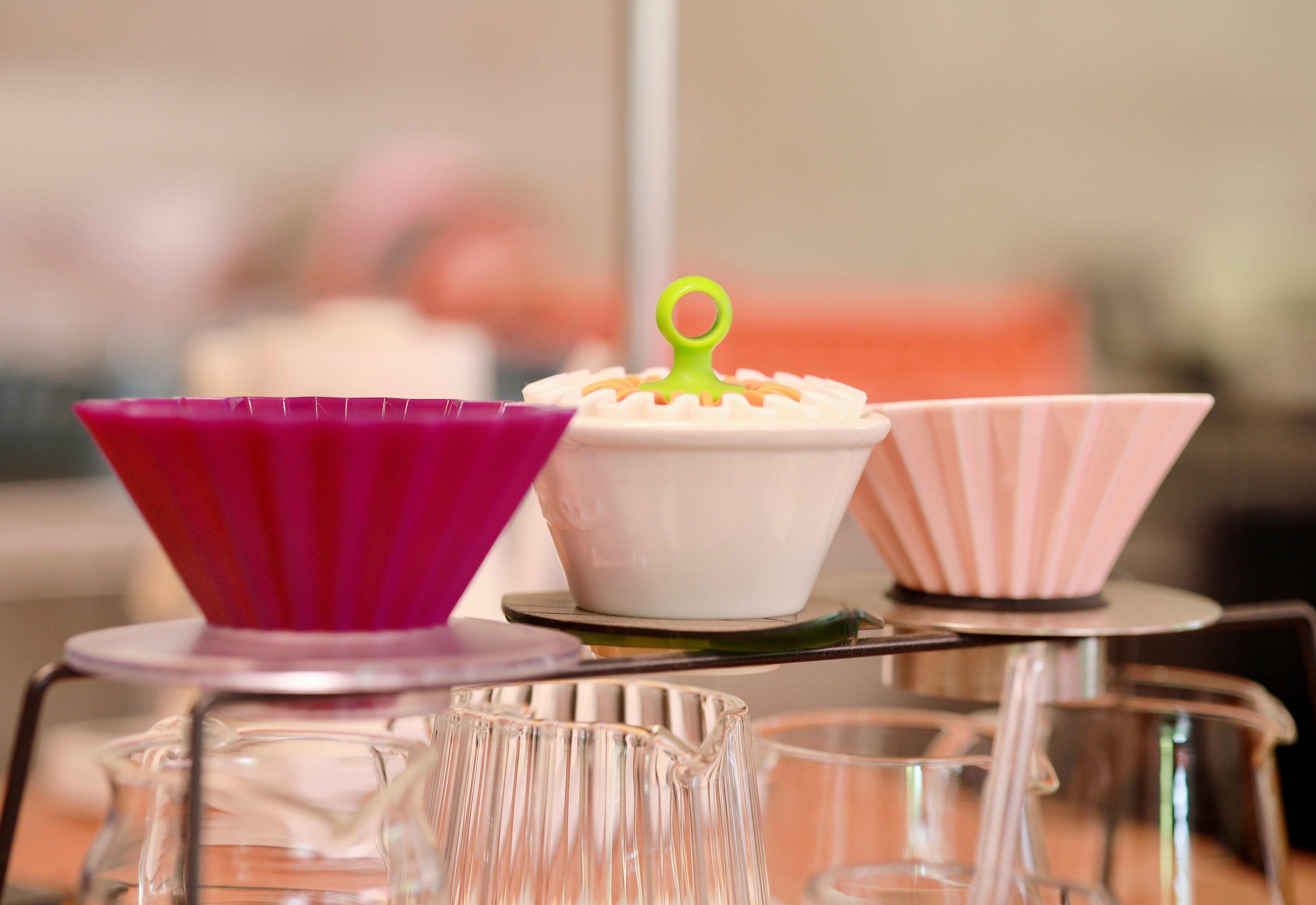 three origami coffee drippers sitting above coffee jugs