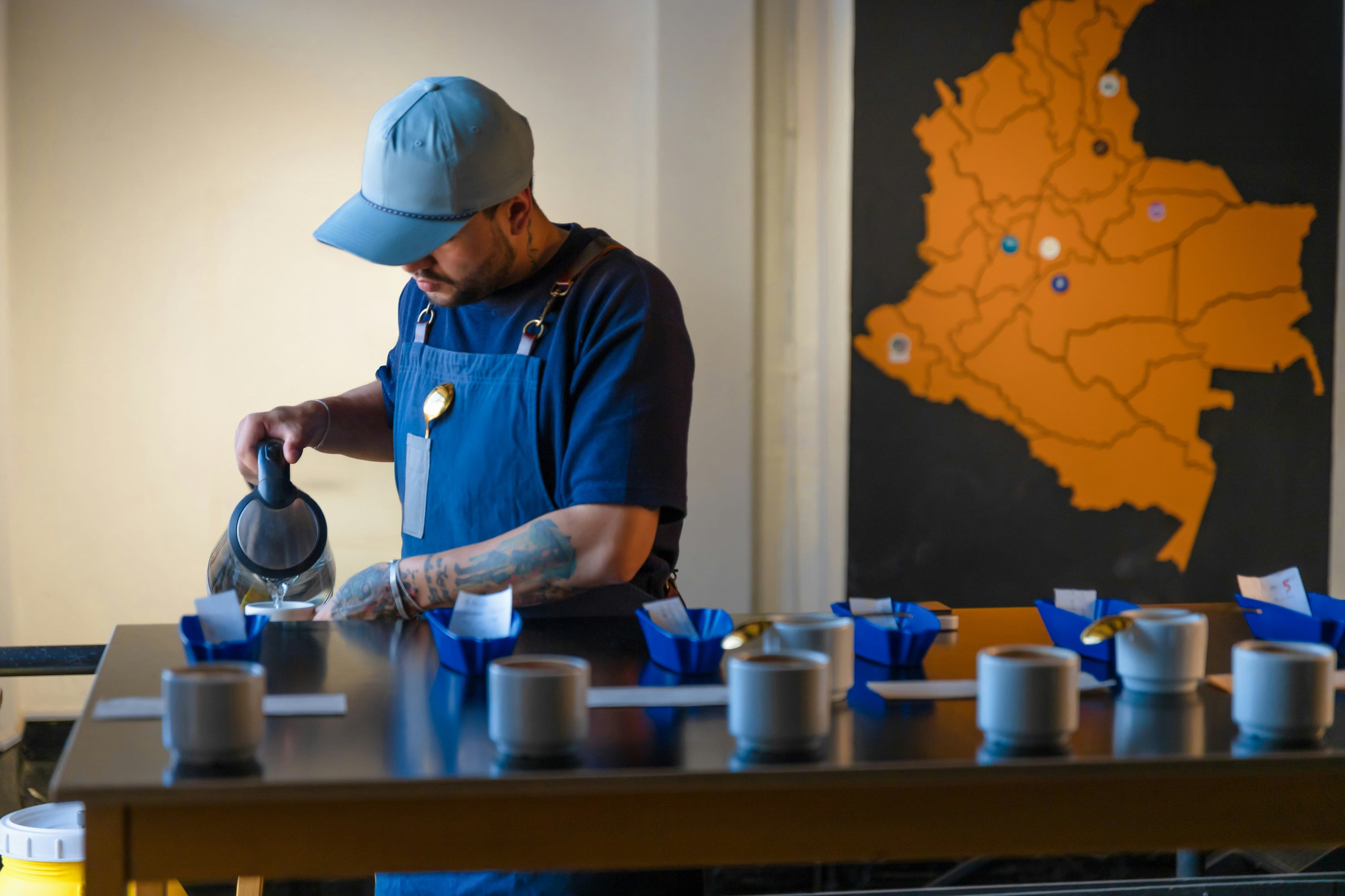 man in blue shirt and cap setting up coffee cupping tasting session
