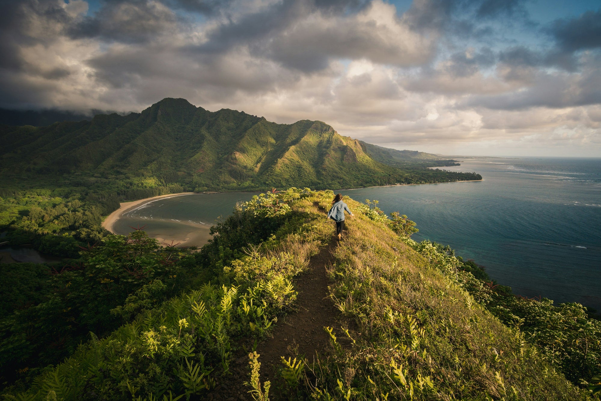 hiker summiting small peak in verdant photo of Hawaii