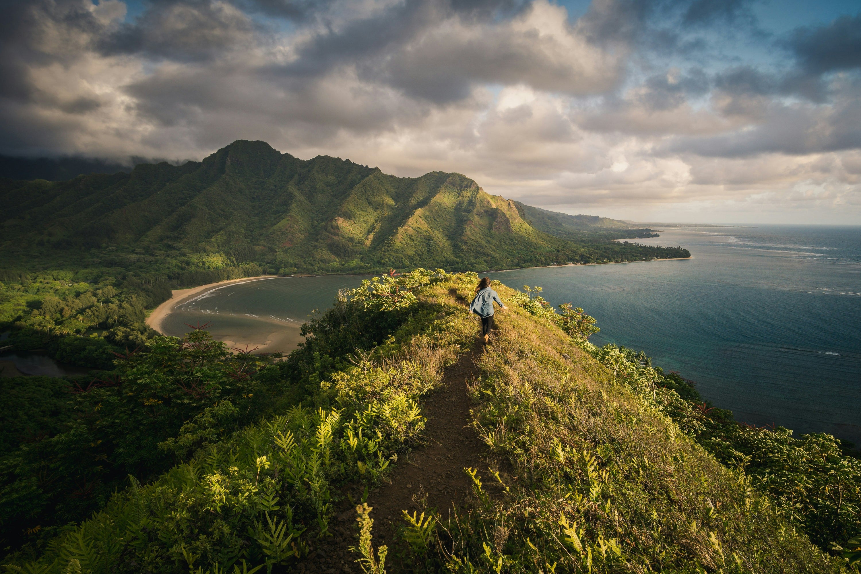 hiker summiting small peak in verdant photo of Hawaii