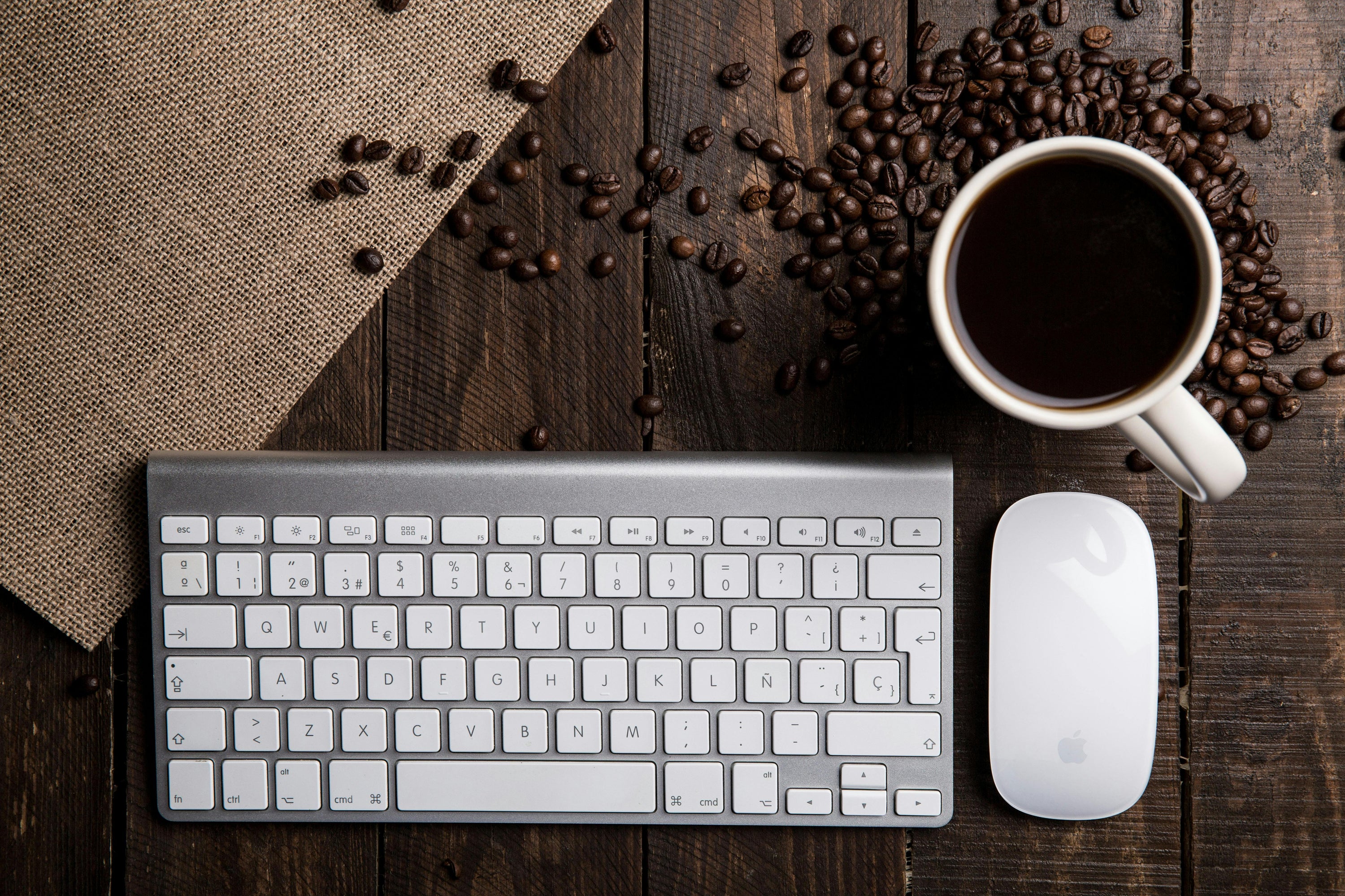 cup of black coffee on desk with silver keyboard