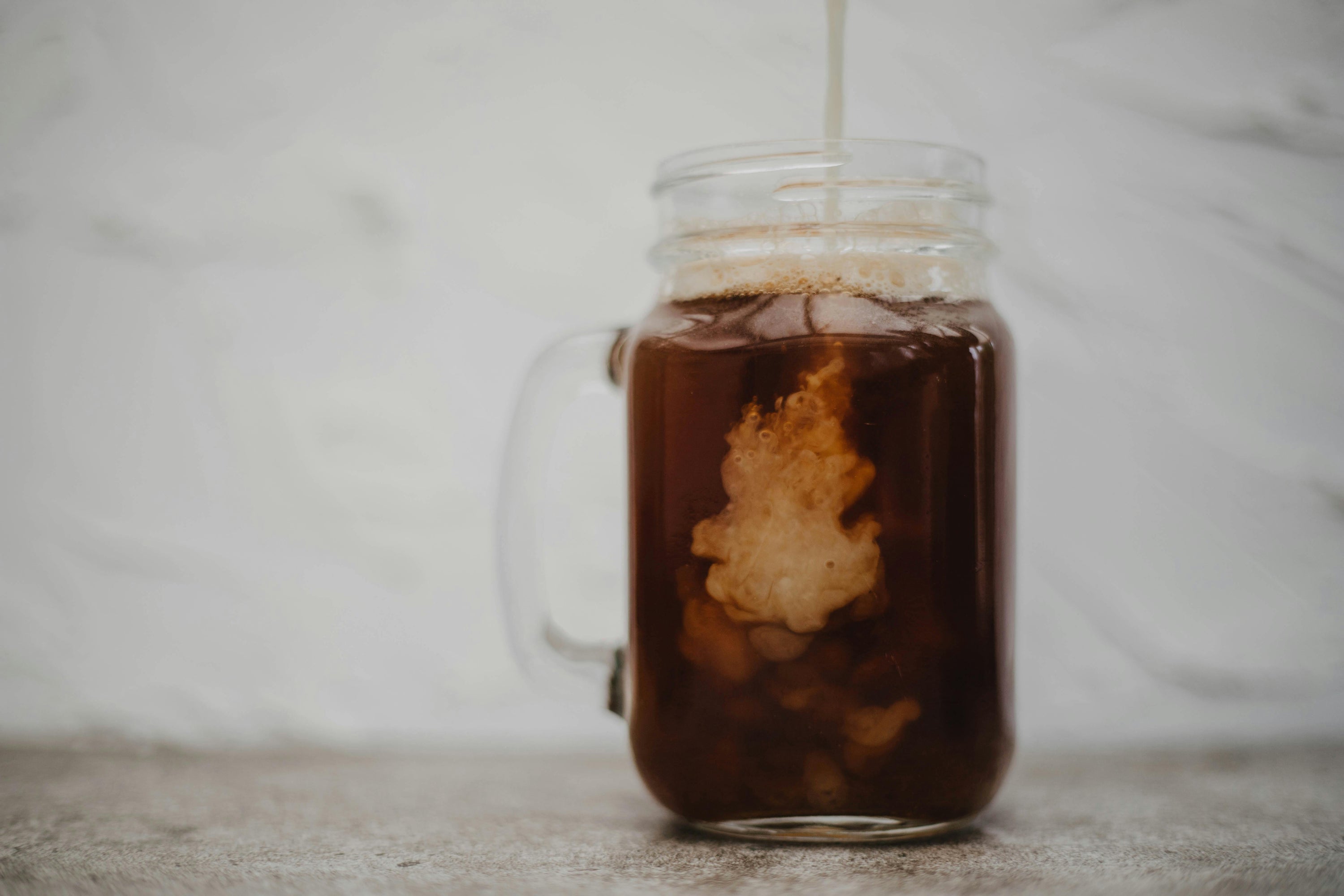 cold brew coffee with cream being poured into it