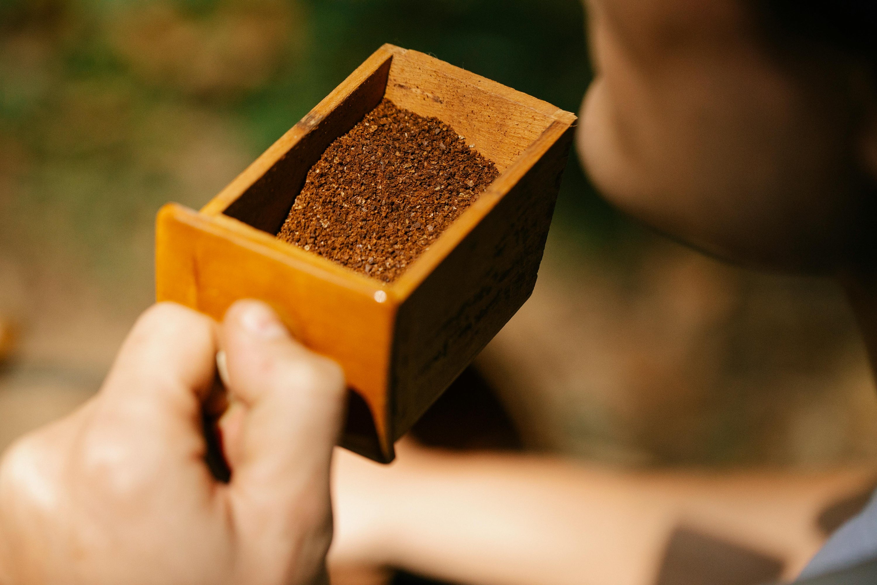 man holding wooden box full of coffee grounds