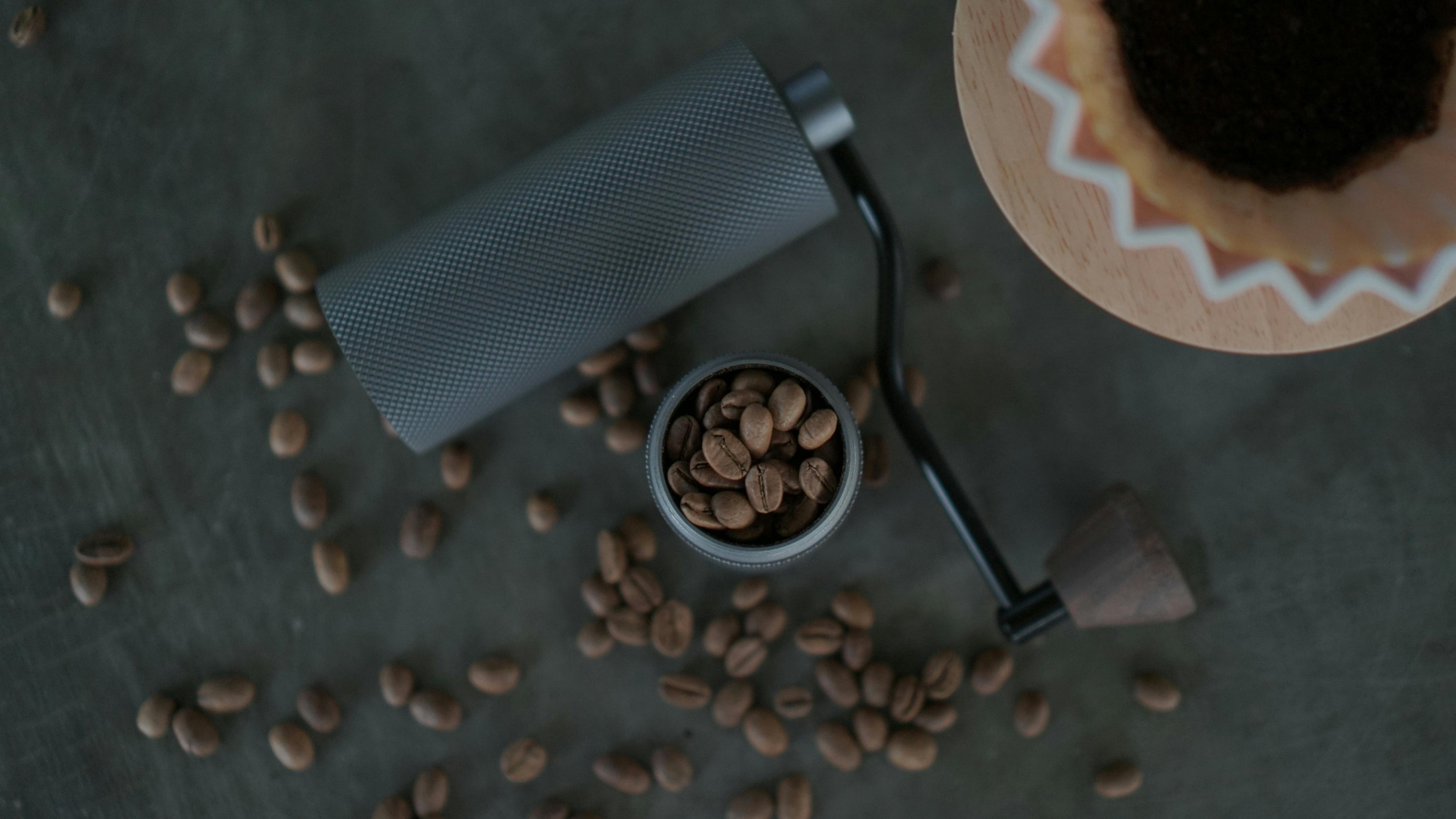 coffee grinder lying flat on countertop surrounded by whole coffee beans