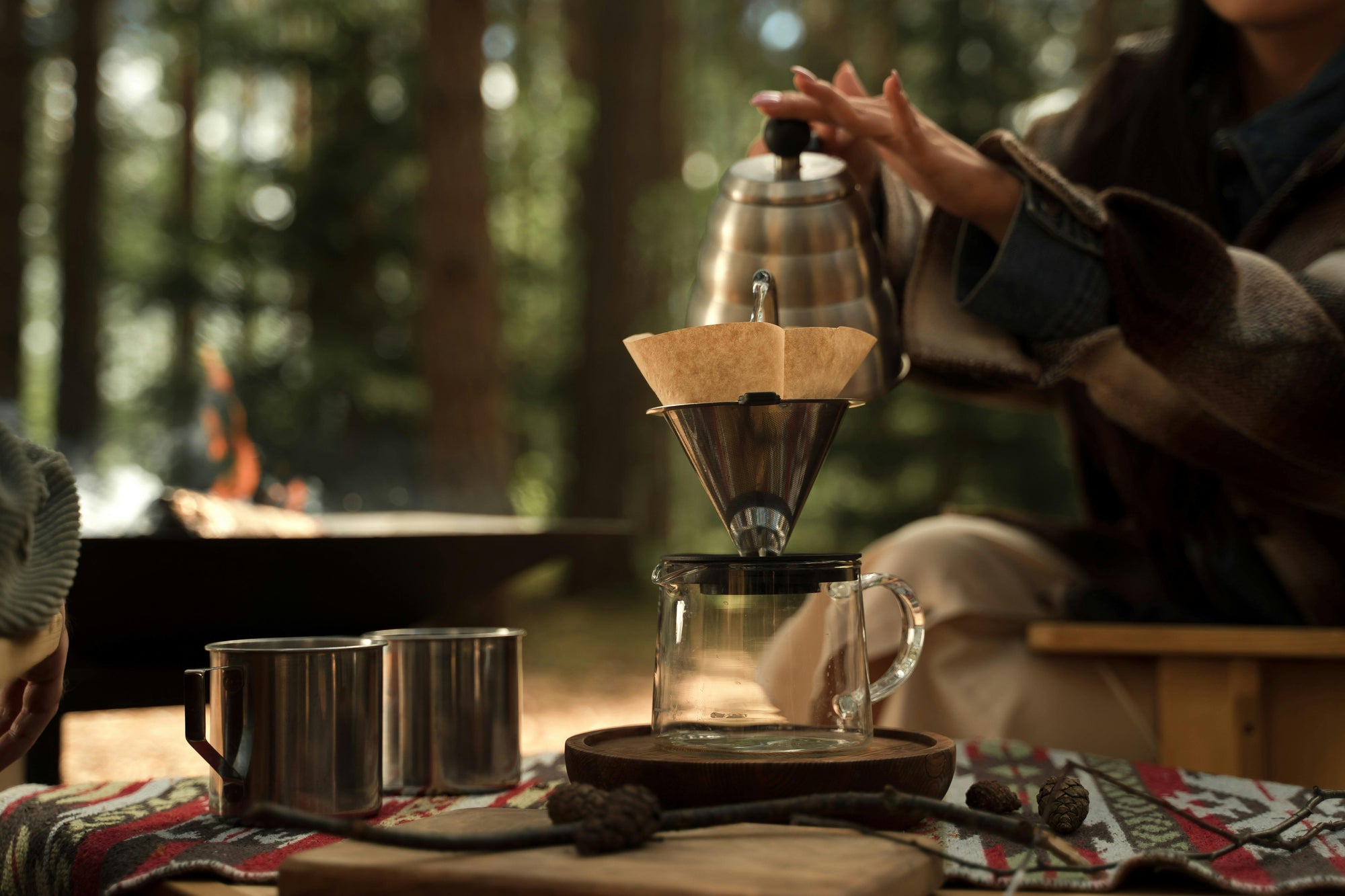 person making pour over coffee in a forest