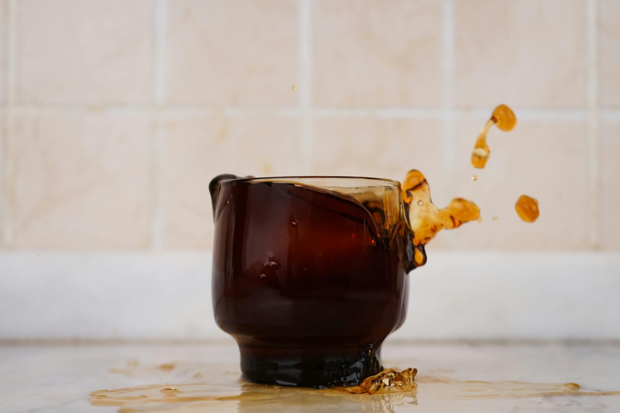 coffee spilling out of glass coffee cup