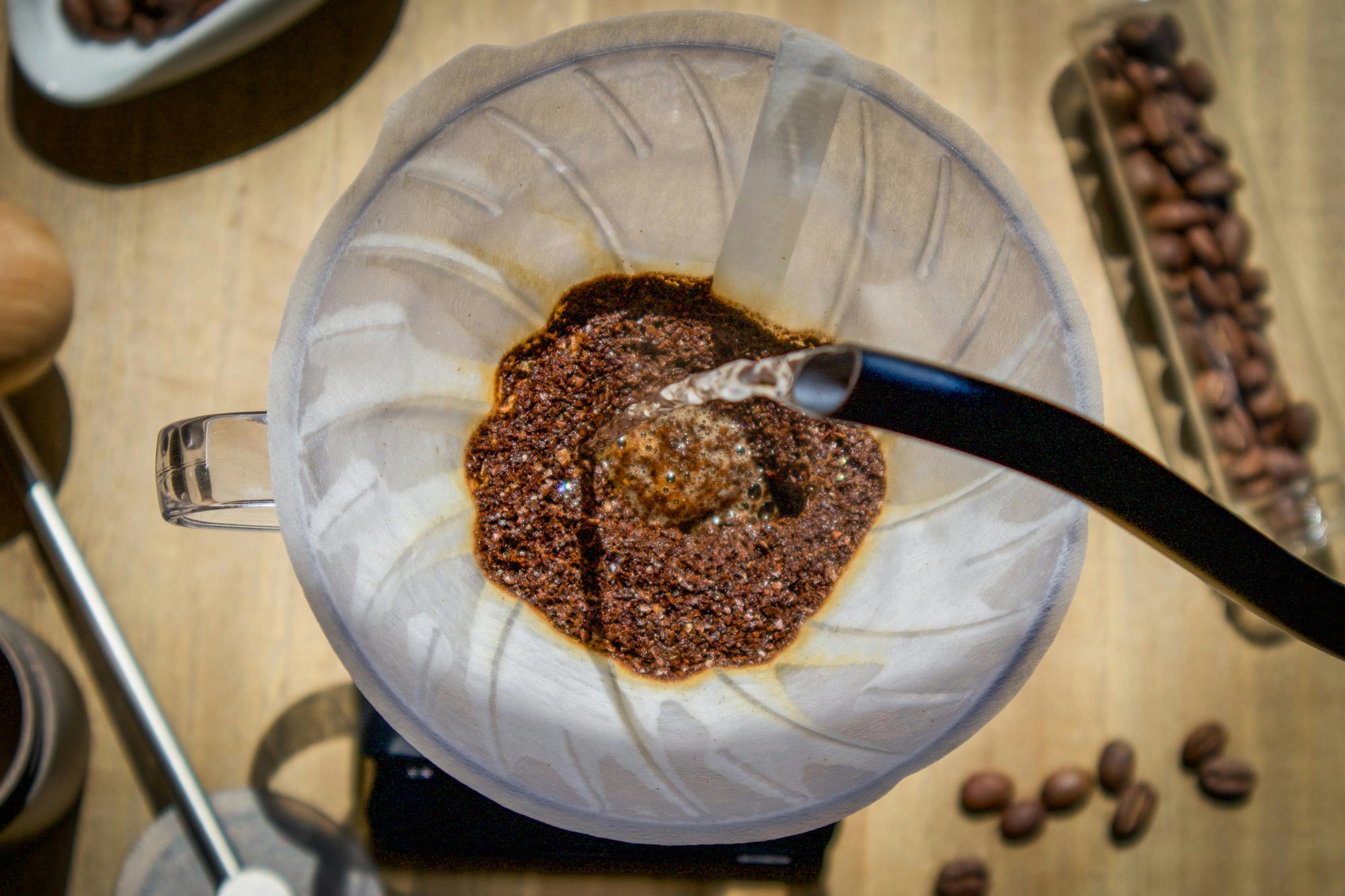 gooseneck kettle pouring water into coffee grounds in pour over coffee maker
