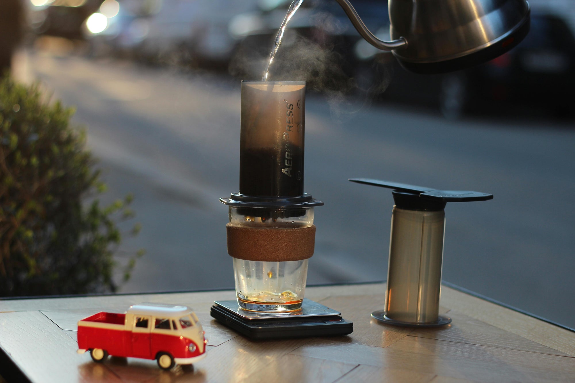 hot water pouring into aeropress on a table, with toy car next to it