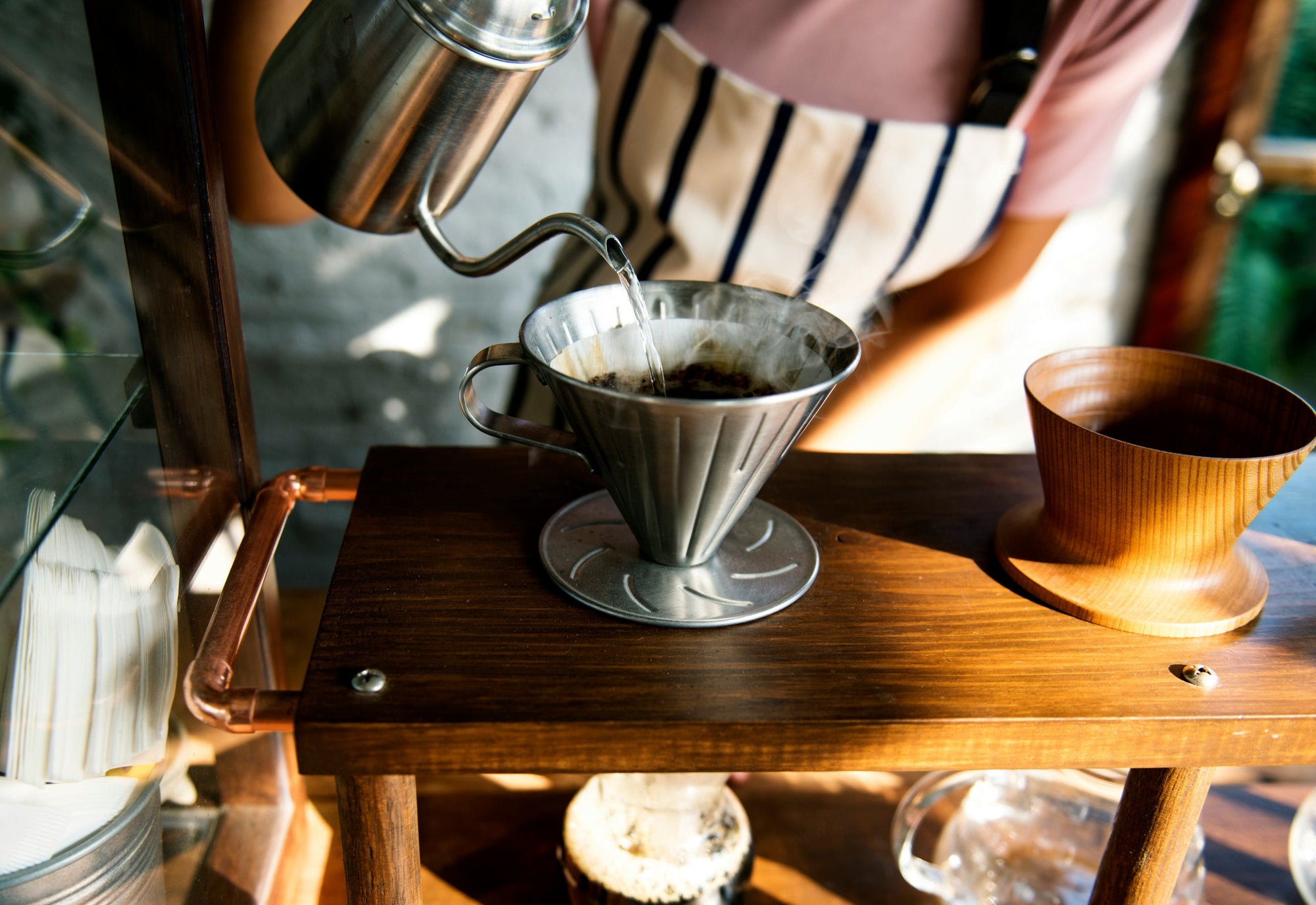 pour over coffee being made with gooseneck kettle on wooden stand