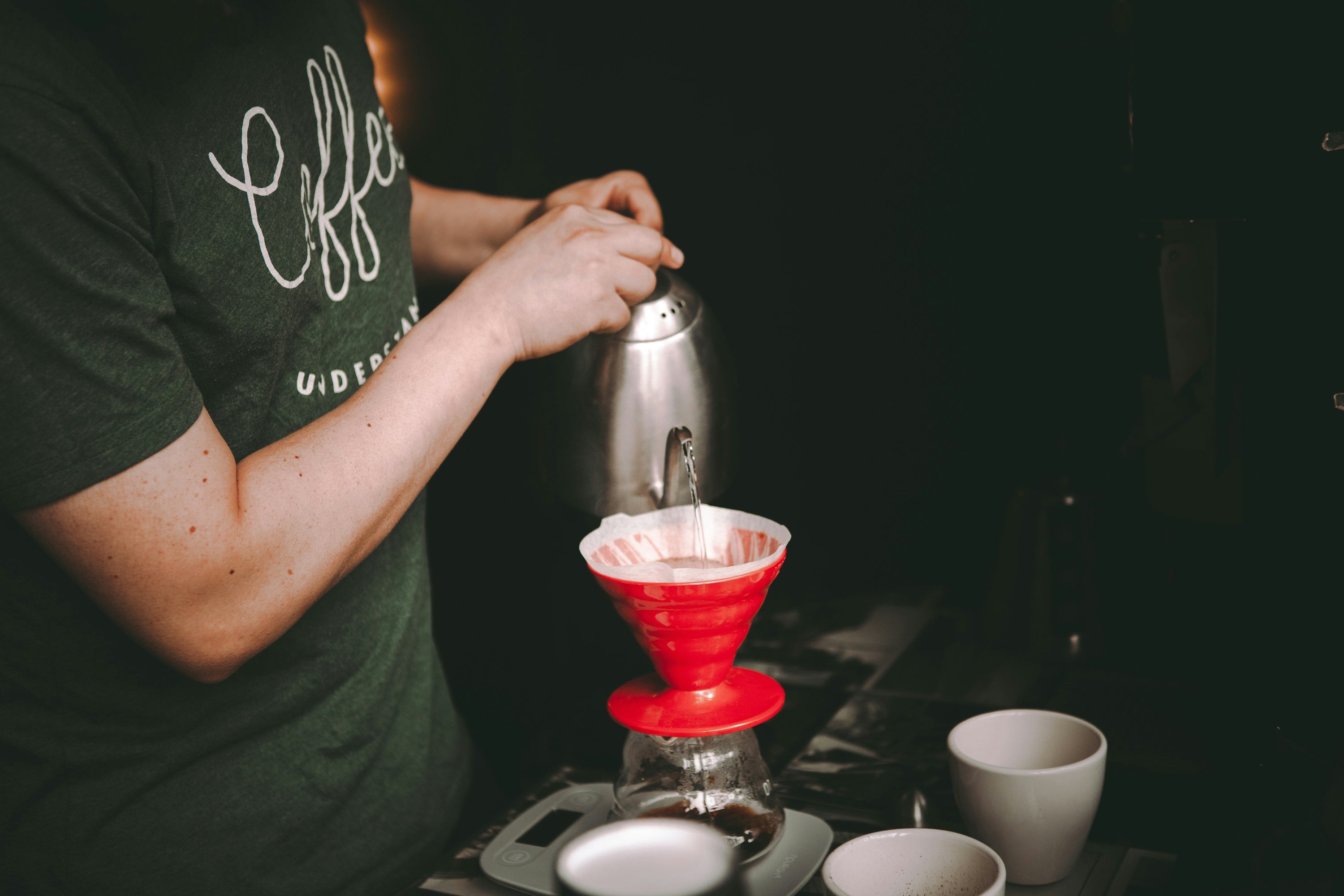red v60 coffee dripper with water being poured into from gooseneck kettle