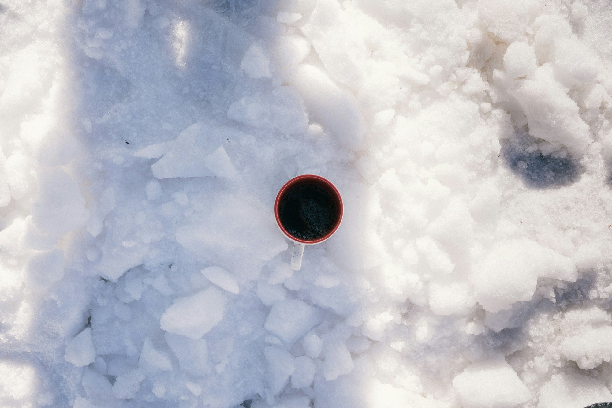 cup of black coffee sitting in white snow