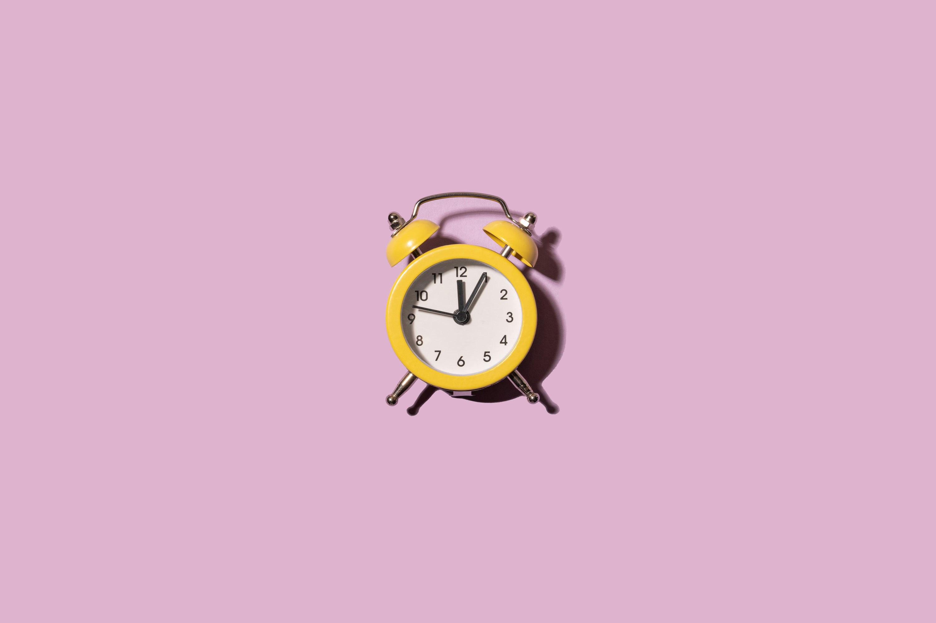 old fashioned alarm on light purple background