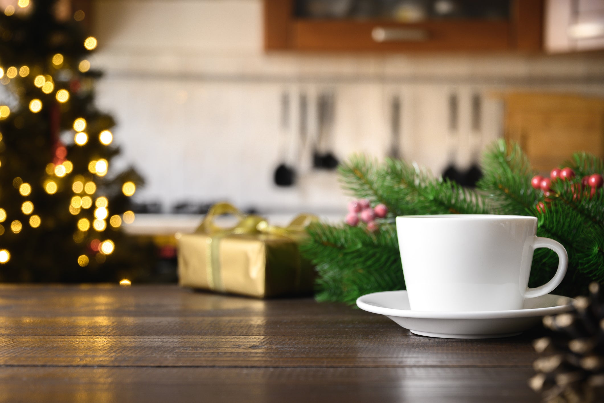 coffee cup on wooden table with christmas tree in background